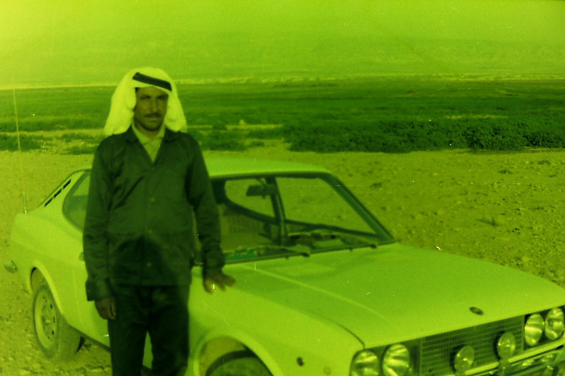 A Fasayel farmer beside his car at the edge of the green fields.