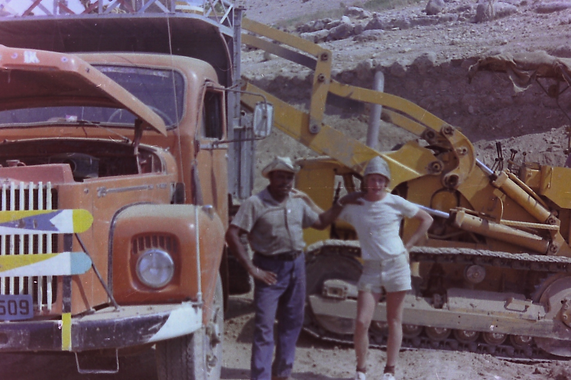 On the dig site — the orange truck, the loader, and the men who ran them.